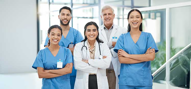 a group of different types of healthcare professionals stand together and smile at the viewer